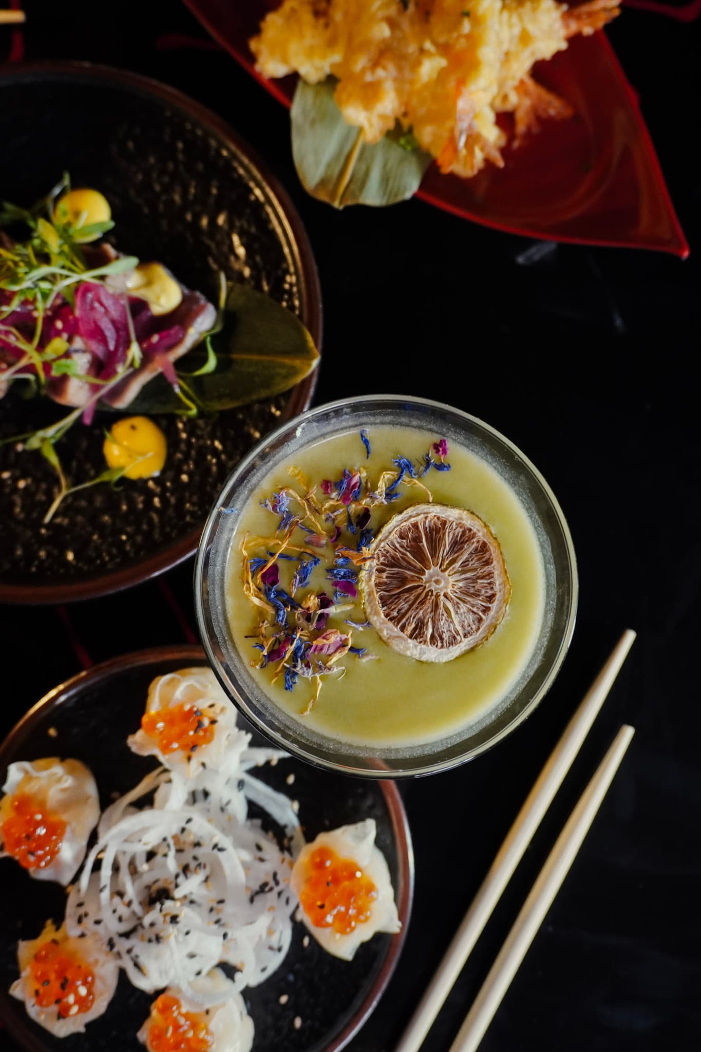 A citrus-forward cocktail with dried lime and floral garnish.